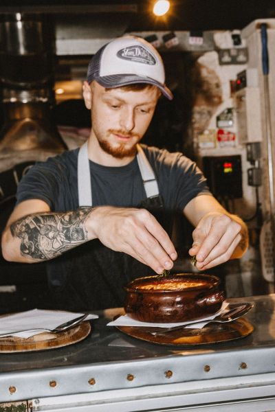 A man cooking in a pub putting final touches on a dish